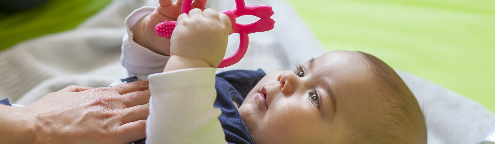 Ein Baby liegt auf einer Decke und spielt.