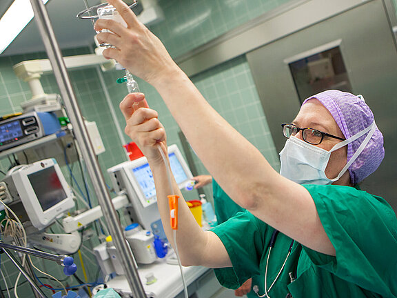 OP-Fachkraft im Operationssaal kontrolliert die Infusion.