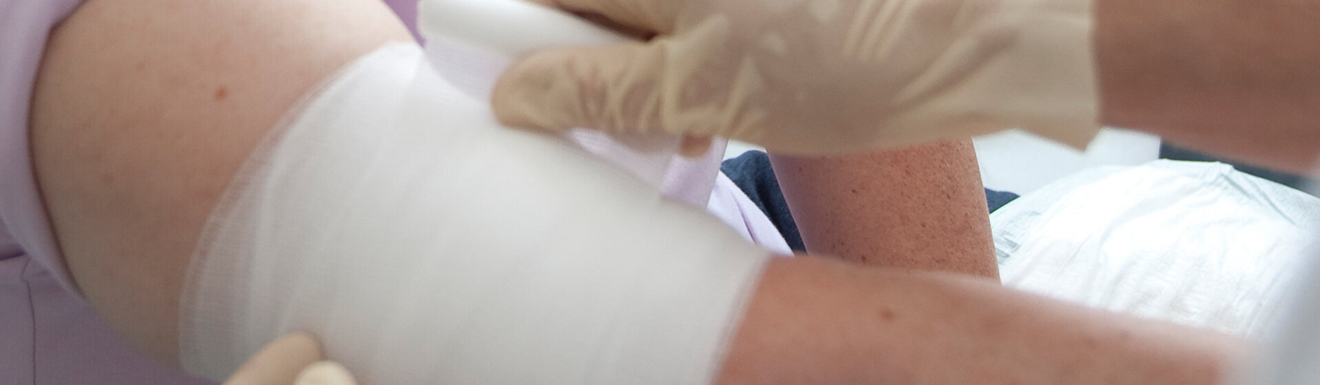 Ein Verband wird am Arm einer Patientin angelegt.