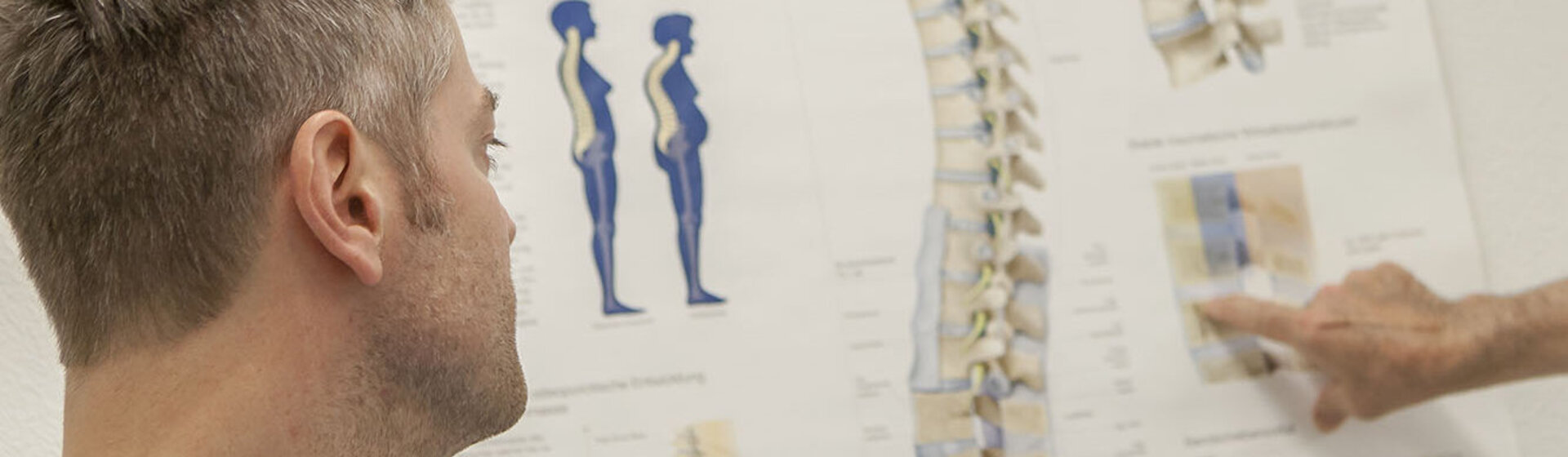 Mediziner zeigt dem Patienten eine Abbildung der Wirbelsäule.