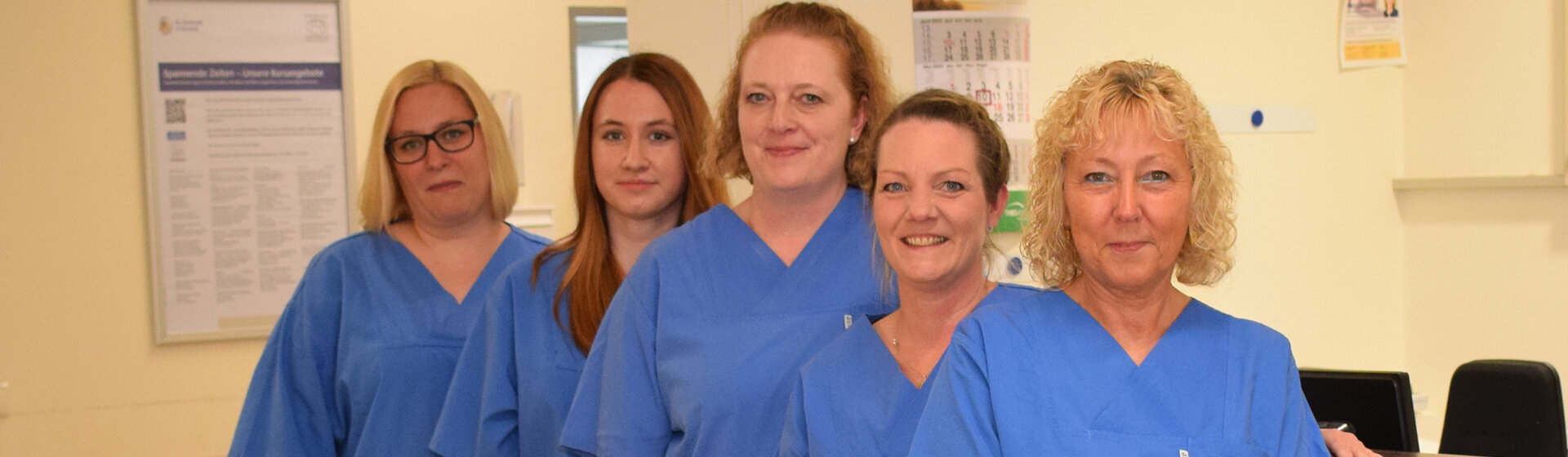 Fünf Pflegefachkräfte lächeln ins Bild.