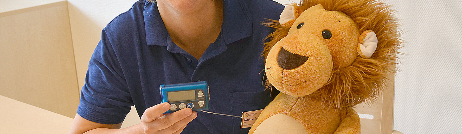 Oberärztin Nadine Scheffler hält ein Blutzuckermessgerät in der Hand, neben ihr am Tisch sitzt ein Kuscheltier (Löwe). Oberärztin Nadine Scheffler hält ein Blutzuckermessgerät in der Hand, neben ihr am Tisch sitzt ein Kuscheltier (Löwe).