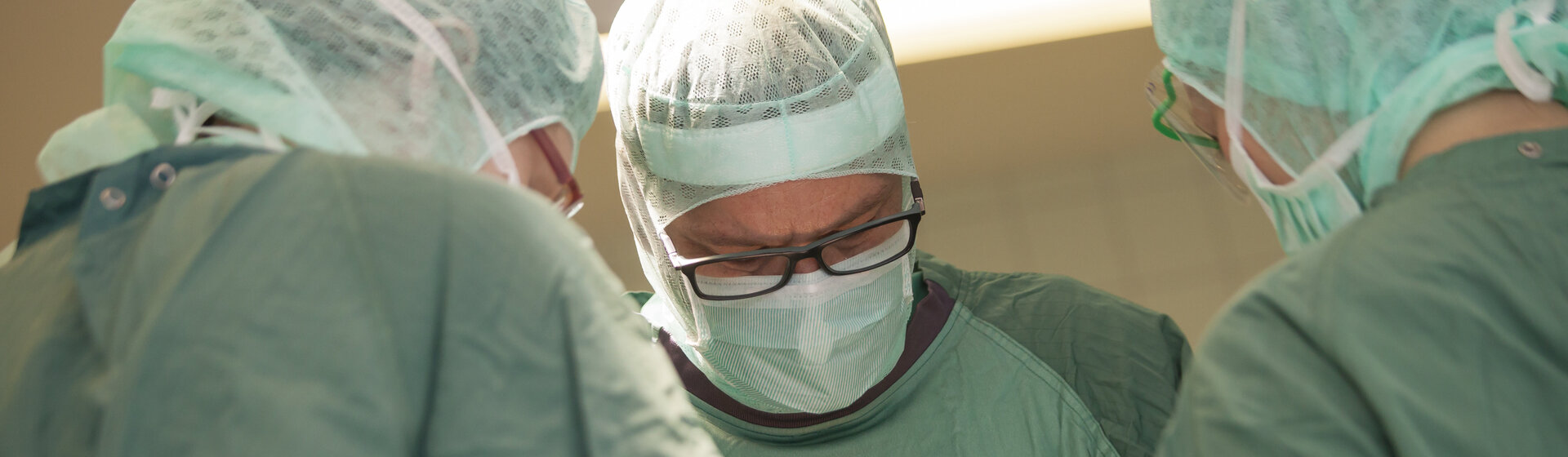 Drei Mediziner in OP-Kleidung stehen am OP-Tisch. Drei Mediziner in OP-Kleidung stehen am OP-Tisch.