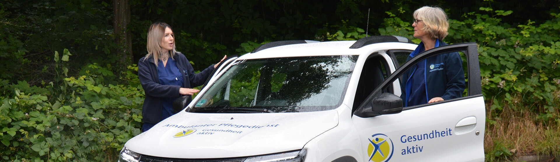 Zwei MitarbeiterInnen des Ambulanten Pflegedienstes steigen in ihr weißes Dienstfahrzeug