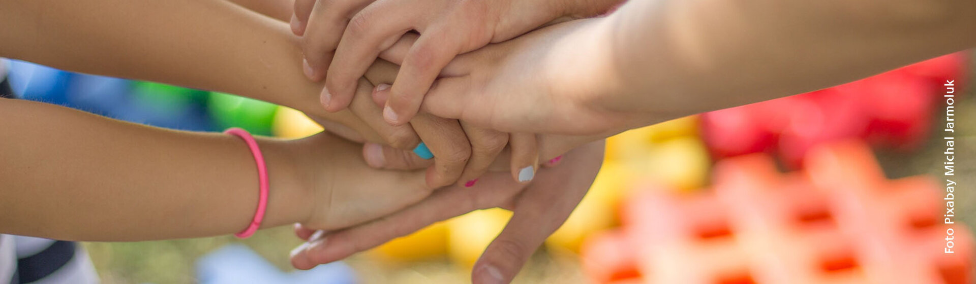 Sieben Kinderhände übereinander treffen in der Mitte zusammen. Sieben Kinderhände übereinander treffen in der Mitte zusammen.