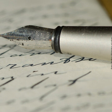 Handschriftlich beschriebenes Blatt Papier und die Spitze eines Füllfederhalters