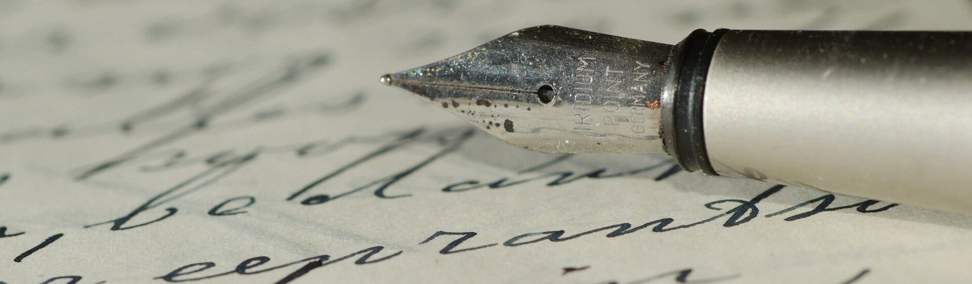 Handschriftlich beschriebenes Blatt Papier und die Spitze eines Füllfederhalters