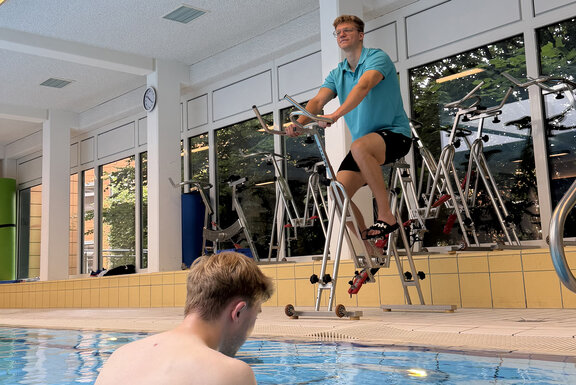 Trainierende Person im Schwimmbad und der MediFit-Trainer beim Aqua-Rider-Kurs.