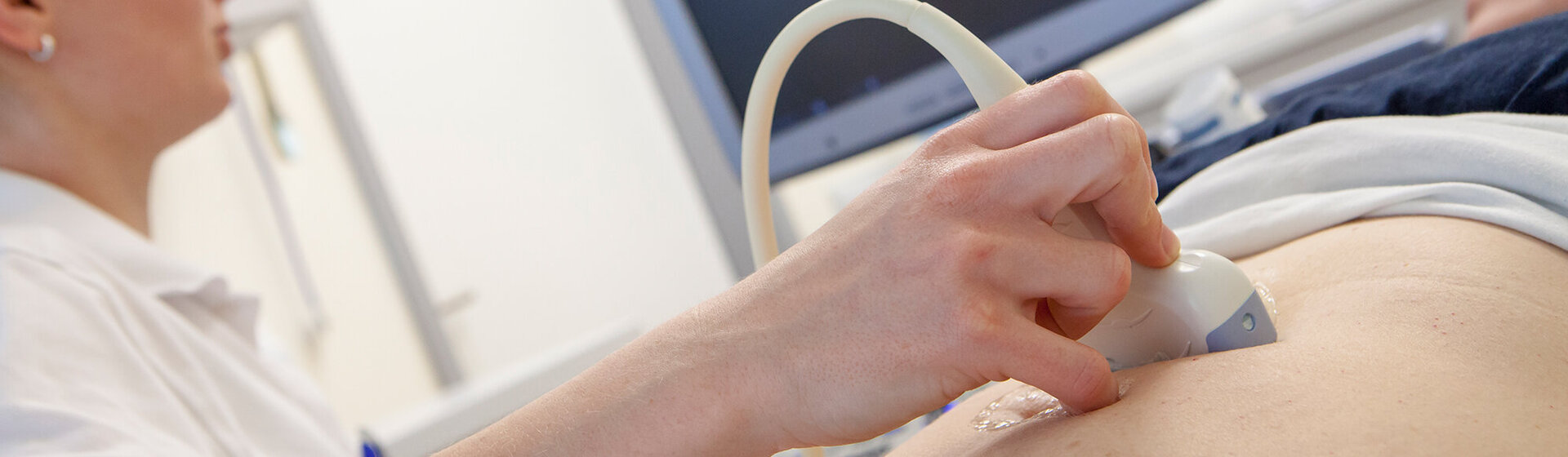 Medizinische Fachkraft hält das Sonografiegerät auf den Bauch der Patientin. Medizinische Fachkraft hält das Sonografiegerät auf den Bauch der Patientin.