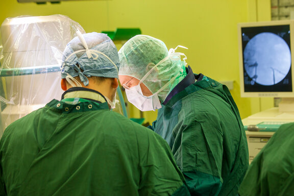 Zwei Operateure in OP-Kleildung im OP-Saal sind konzentriert auf die Operation.