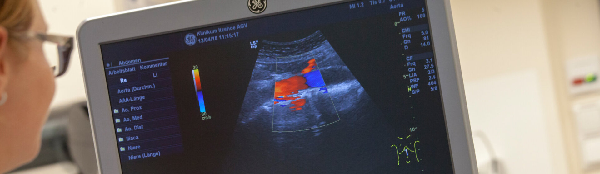 Medizinische Fachkraft hält das Sonografiegerät auf den Bauch der Patientin.