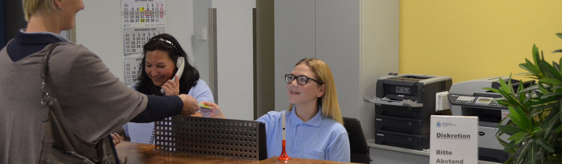 Eine Patientin wird am Anmeldetresen der HNO-Praxis begrüßt.