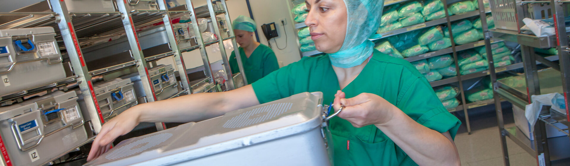 Operationstechnische Assistentin (OTA) nimmt einen Sterilgutcontainer mit OP-Instrumenten aus dem Regallager.