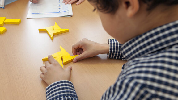Ein Junge sitzt am Tisch und puzzelt ein Holz-Puzzle.
