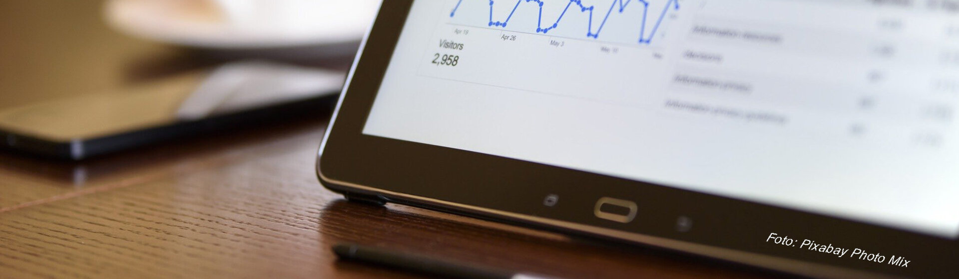 Tablett, Handy und eine Tasse stehen auf einem Tisch.