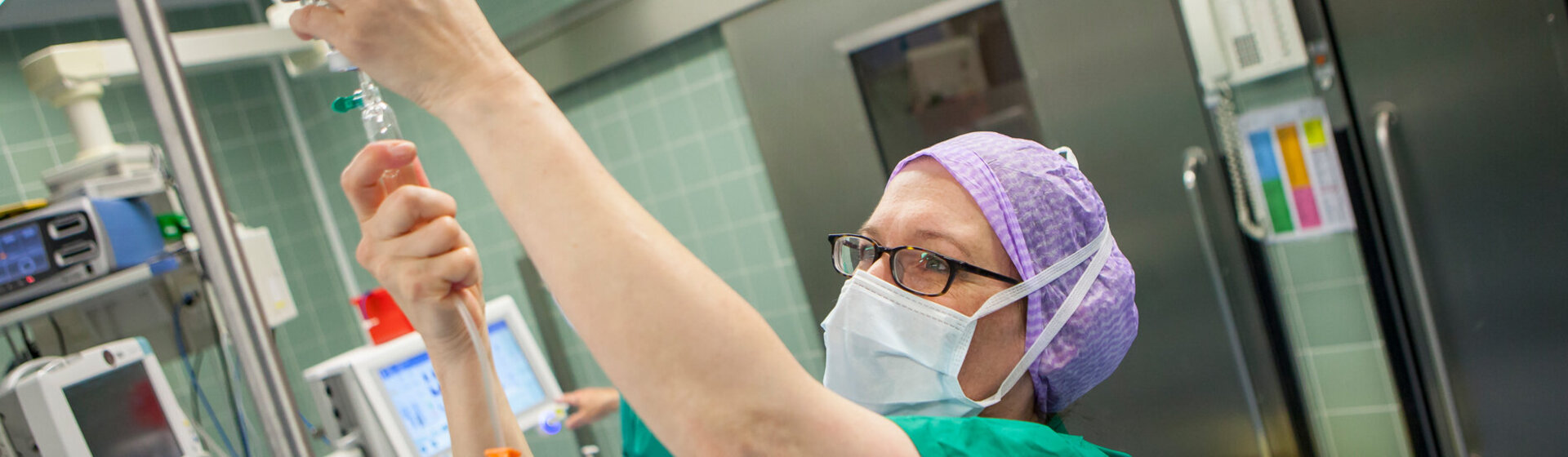 OP-Fachkraft im Operationssaal kontrolliert die Infusion.