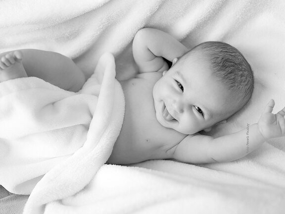 Schwarz-Weiß-Foto eines fröhlich lächelnden Babys.