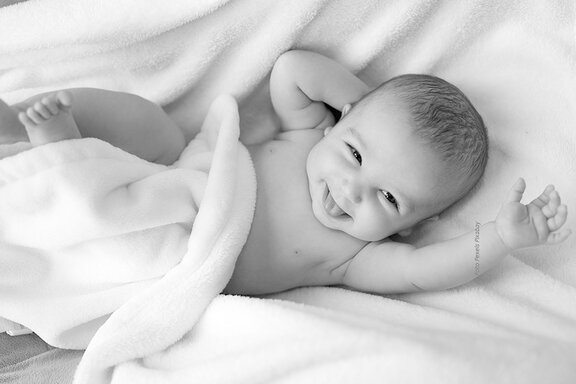 Schwarz-Weiß-Foto eines fröhlich lächelnden Babys.