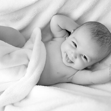 Schwarz-Weiß-Foto eines fröhlich lächelnden Babys.