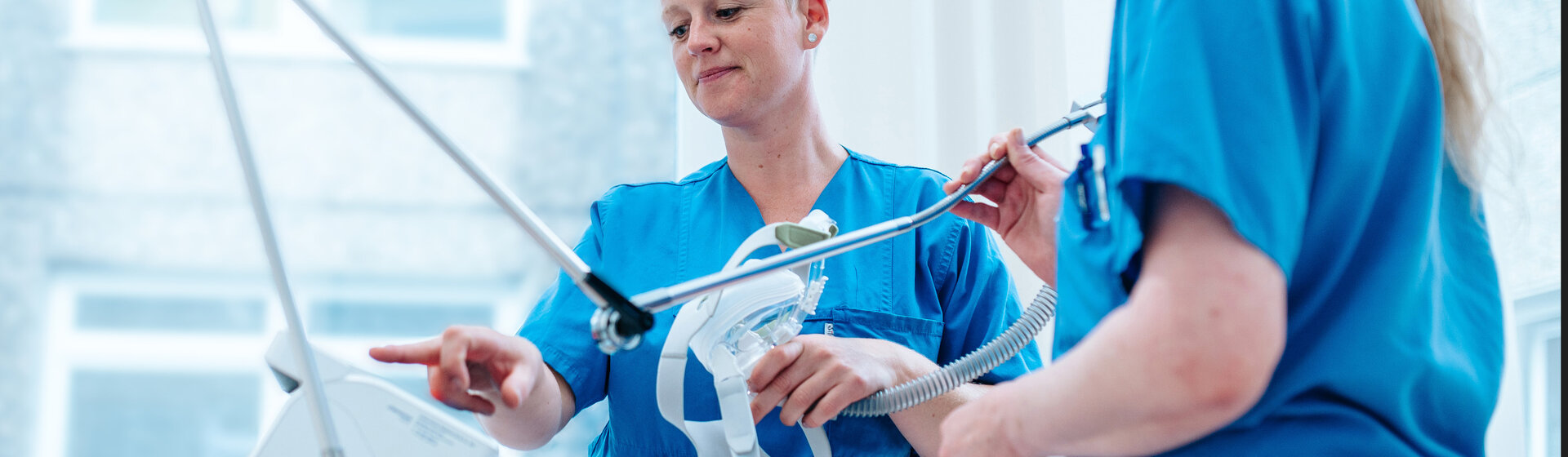 Zwei Pflegefachkräfte halten Beatmungsmaske in der Hand.