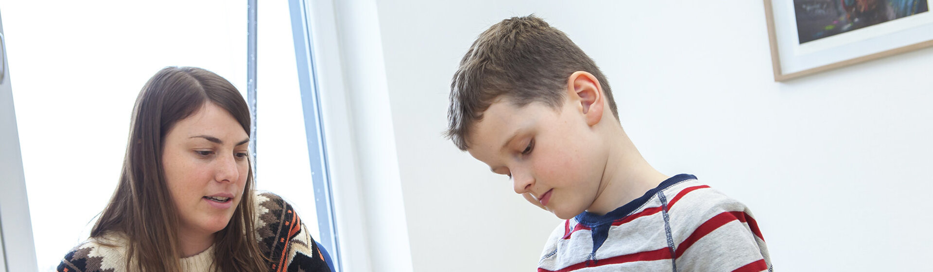 Eine Psychologin unterhält sich mit einem Jungen, der mit Spielzeugfiguren spielt.